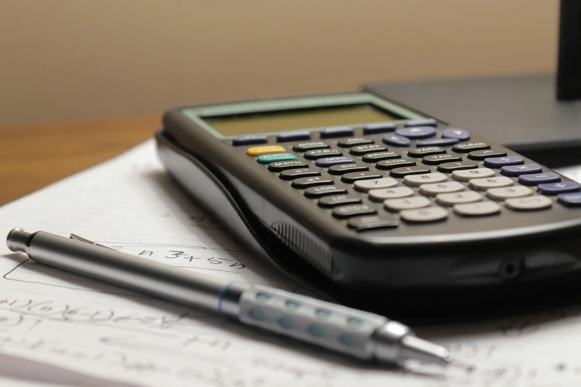 A calculator and pencil on a worksheet, used to add up monthly Shopify app subscription costs