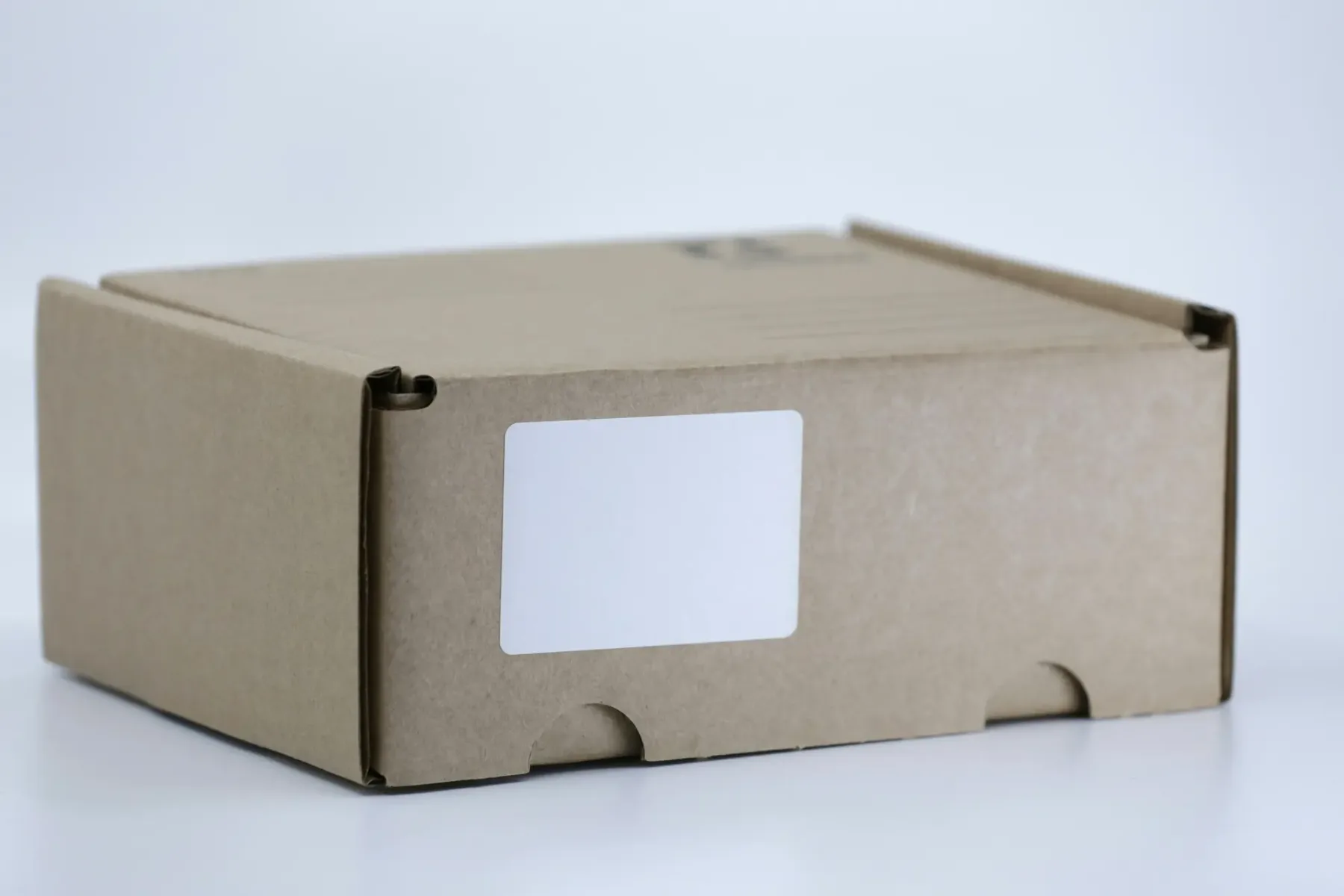 A plain cardboard parcel with a blank shipping label, representing delivery and returns information