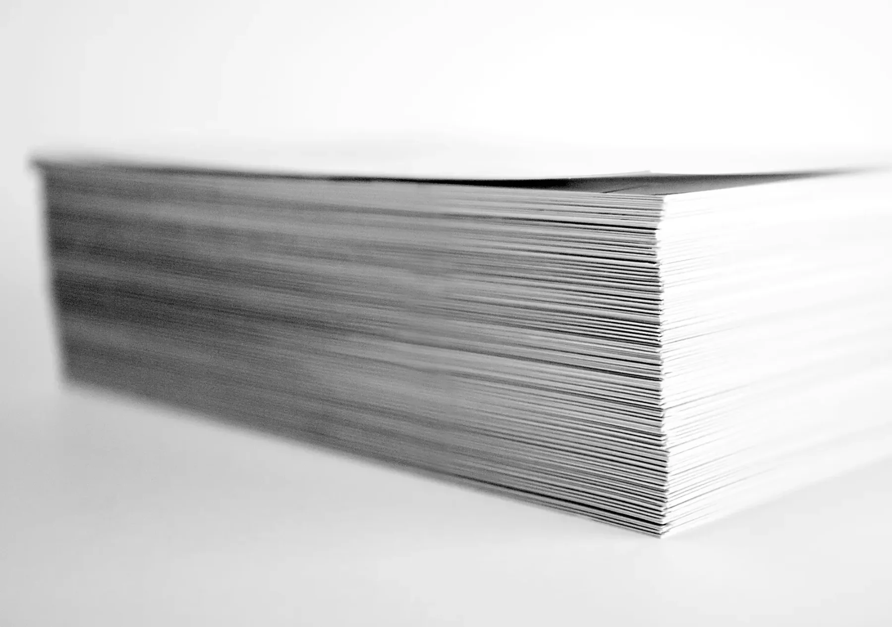A tall stack of photo prints, standing in for product image files that are far larger than the page needs