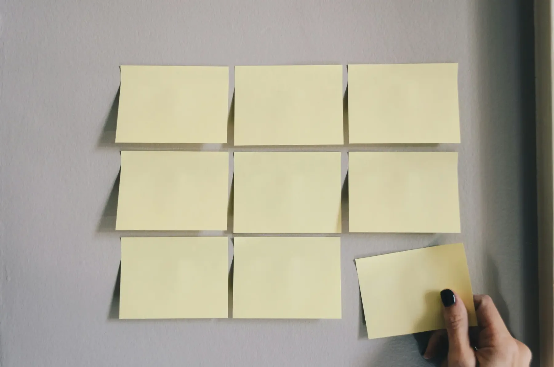 A grid of sticky notes on a wall being arranged, representing planning which metafields to create