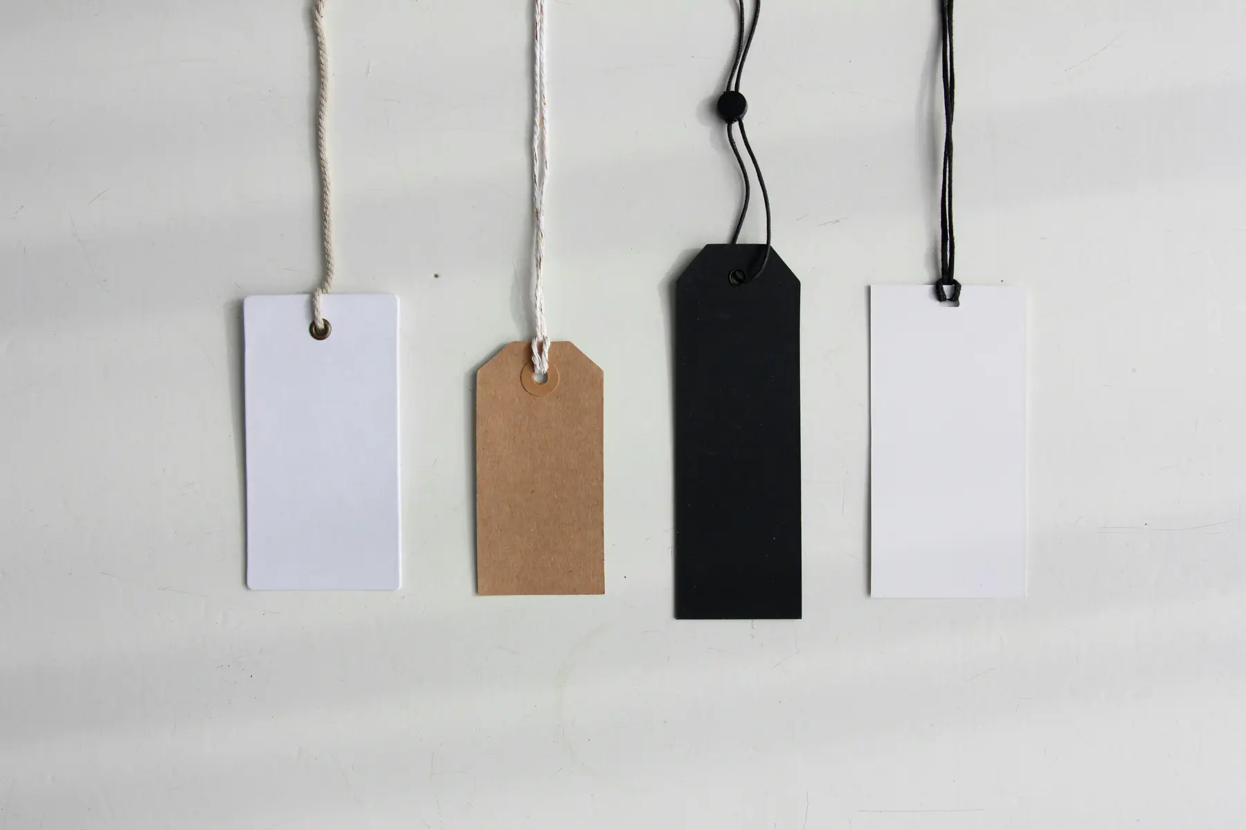 Blank hang tags on strings, representing the product attributes that need to be filled in for AI discovery